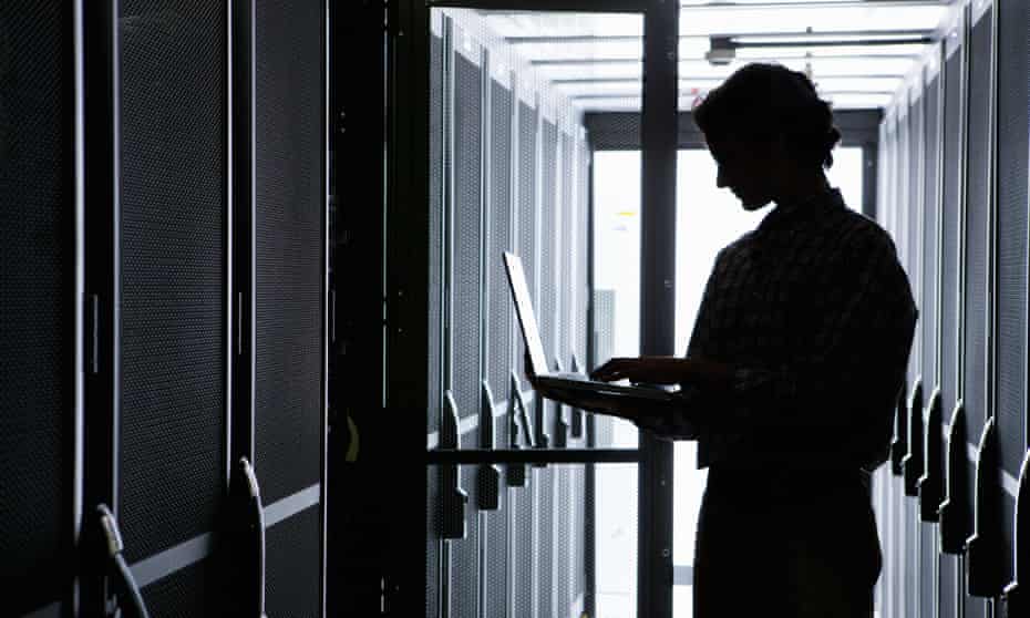 Silhouette of a person with a laptop beside office cabinets