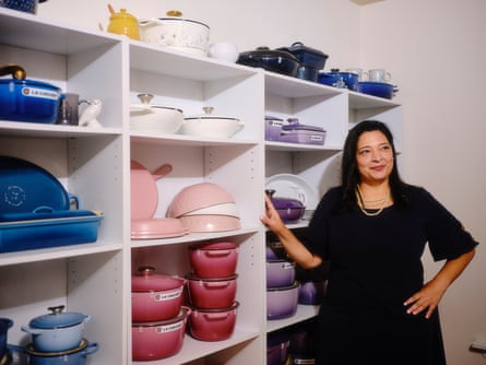 woman standing next to shelves with lots of le creuset pots