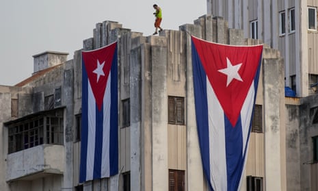 A man walks along the ledge of a building after hanging two giant Cuban flags, next to the US embassy in Havana.