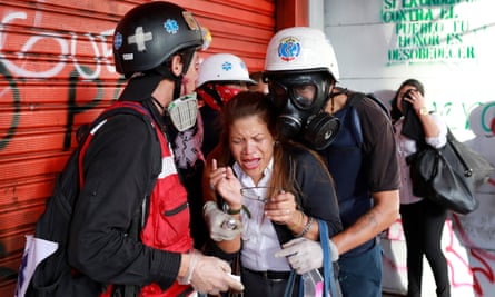 A woman overcome by tear gas receives assistance from volunteers during a rally against President Maduro’s government in Caracas