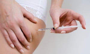 Woman self-administering insulin with a hypodermic syringe. 