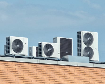 Rooftop air conditioning units for building climate control against a blue skySeveral white air conditioning condenser units are installed on the flat roof of a building. The units vary slightly in size and are set against a clear blue sky with a few wispy clouds.