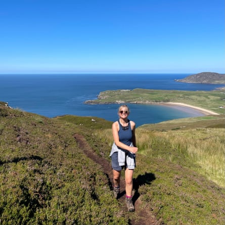 Helen Pidd walking with deserted sandy cove below