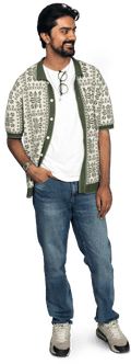 A bearded man stands wearing patterned shirt, blue jeans and trainers