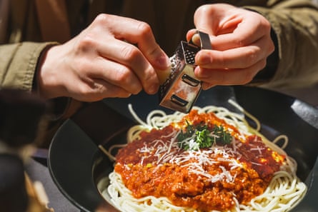 Hands grating delicious parmesan cheese on freshly made italian bolognese pasta