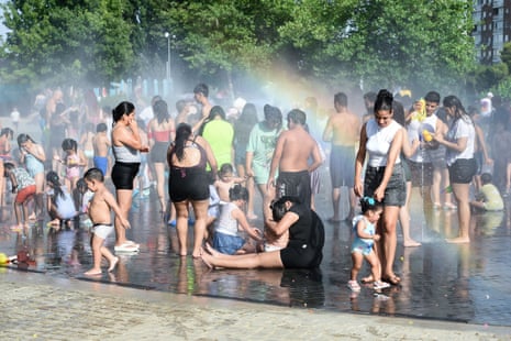People cool off at a fountain in a park in Madrid, Spain.
