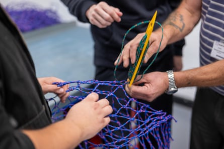 A teacher and student working on a fishing net