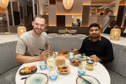 Peter and Akshat smiling at the camera while sitting at a restaurant table