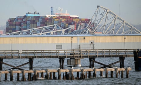 The steel frame of the Francis Scott Key Bridge sit on top of a container ship after the bridge collapsed collapsed in Baltimore.