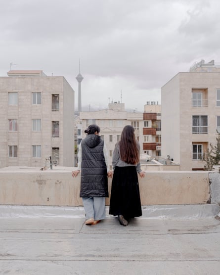 Two women, backs to camera, on a balcony overlooking Tehran