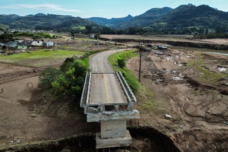 Bridge abruptly stops on bank of river where a section of it has been destroyed, leading to a steep drop