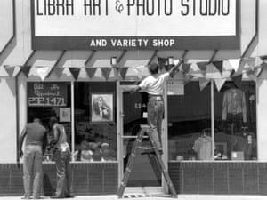 Photographer Willie Robinson puts decorations on his storefront in preparation for Juneteenth celebrations, in 1989