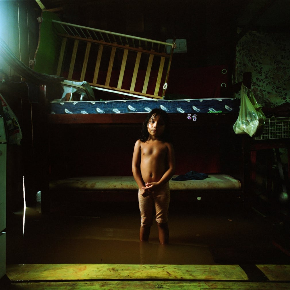 A girl stands in her flooded house