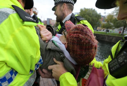 A pro-Palestine activist is carried away by police officers, his feet off the ground