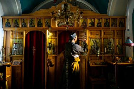 Father Iusif lights candles inside his church that he built.