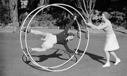 ‘Tennis player Miss Mary Heeley in an exercise wheel being given a push by fellow athlete Miss Hardwick’