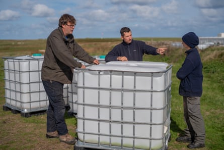 People stand next to large water containers