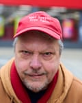 A head-and-shoulders portrait of him wearing a caramel hoodie and a red baseball cap emblazoned with “Make Newport Great Again”