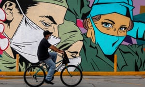 A man rides a bike past a coronavirus-related mural by urban artists Mick Martinez and ‘Were Torres’ in Ciudad Juárez, Chihuahua state, Mexico, at the weekend.