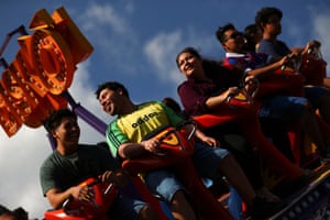 A group of people laugh as they sits on a spinning and swinging fairground ride during the festivities of El Divino Salvador del Mundo