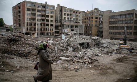 'He works hard': Voters in Turkey's earthquake zone back Erdoğan in second round | Türkiye 1 A woman walks past badly damaged buildings.