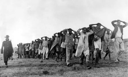 Nairobi, Kenya, 1952. A photograph showing a round up of Mau Mau suspects being led away for questioning by police with their hands on their heads after being captured in a raid in the Great Rift Valley in Kenya.Nairobi, Kenya, 1952, A photograph showing a round up of Mau Mau suspects being led away for questioning by police with their hands on their heads after being captured in a raid in the Great Rift Valley in Kenya (Photo by Popperfoto/Getty Images)