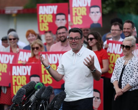 Andy Burnham giving a speech to the press surrounded by people holding: 'Andy, for us' signs