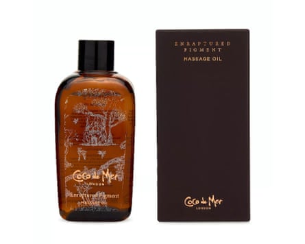 A bottle of Coco de Mer Enraptured Figment Massage Oil next to its chocolate brown and gold packaging box.