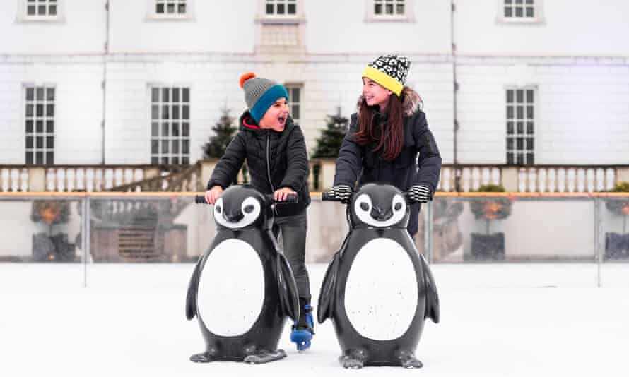 Two children holding penguin skate-aids on the ice at the Queen’s House Ice Rink, Greenwich