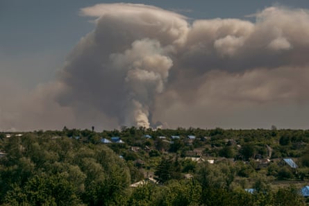 A cloud of smoke from a forest fire rises across the skyline