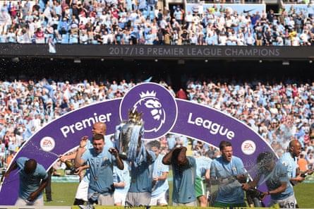 Manchester City players celebrate with the Premier League trophy on the Etihad Stadium's pitch in May 2018.