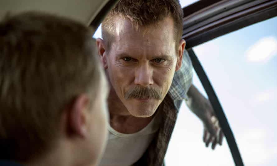 Kevin Bacon in a police car.
