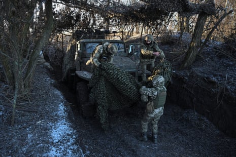 Service members of the Ukrainian armed forces take off a camouflage net from a BM-21 Grad multiple rocket launch system at their position in a frontline in the Donetsk region.
