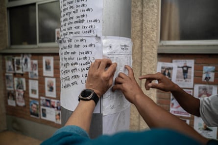 Relatives search through lists of people reported missing outside hospital in Kathmandu.