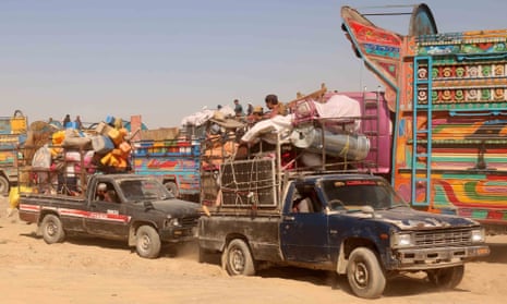 Trucks loaded with people and possessions wait in line