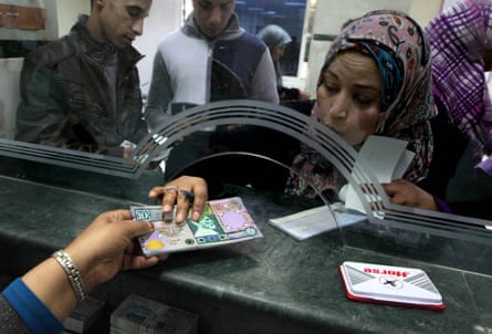 A Libyan bank cashier gives a client outdated bank notes, which had been removed from circulation and reissued due to cash shortage in Tripoli in 2011.
