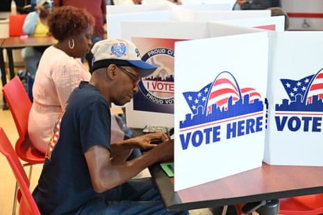 A man in a baseball cap fills out his ballot beside a "Vote Here" sign in St. Louis