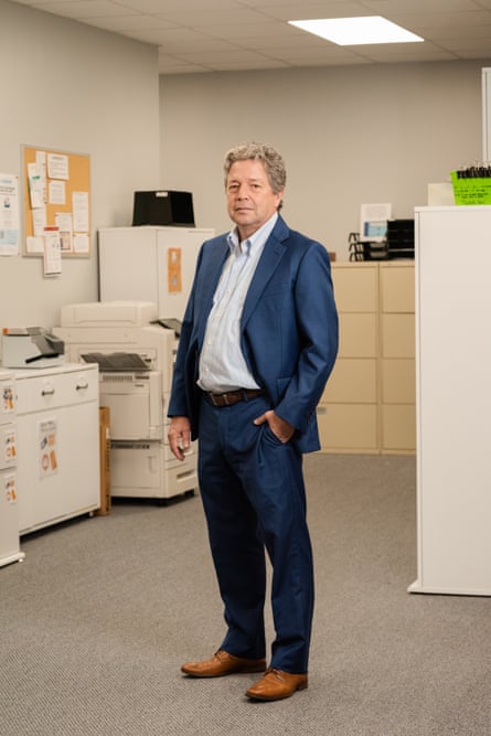 man in blue suit stands in office with one hand in pocket