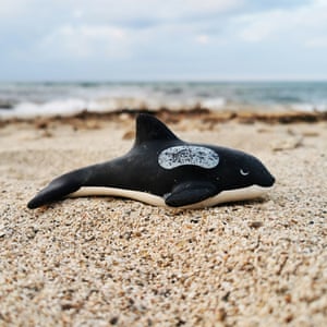 A plastic toy whale on the beach.