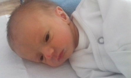 Ollie as a newborn baby lying in a crib