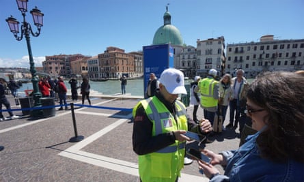 A steward checks tickets as people enter Venice on 25 April 2024, after the launch of a five-euro entrance ticket scheme.
