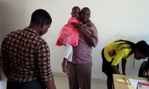Dodo Boniface carries his daughter, Dainess, during a weigh-in at Bugando Medical Centre in Mwanza. Doctors are trying to assess whether Dainess is strong enough for a course of chemotherapy.