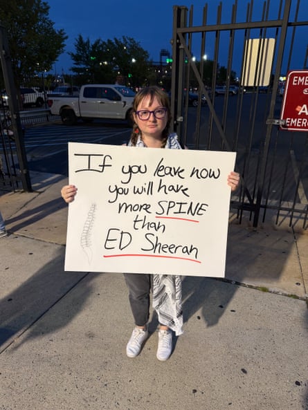 a woman holds a sign outside a stadium