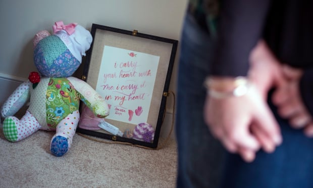 A shadow box of memories of their daughter, including her hand and foot prints, sits with a teddy bear.