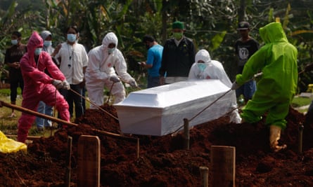 Workers bury a person who died with Covid-19 during a funeral at a cemetery in Depok, Indonesia