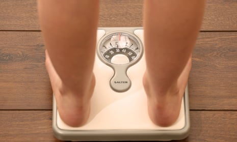 A girl weighs herself on a set of scales