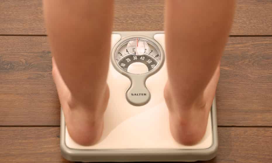 A girl weighs herself on a set of scales