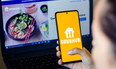 a woman holds a smartphone with the Grubhub Inc. logo displayed on the screen
