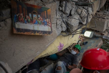 A man crawls under a collapsed wall