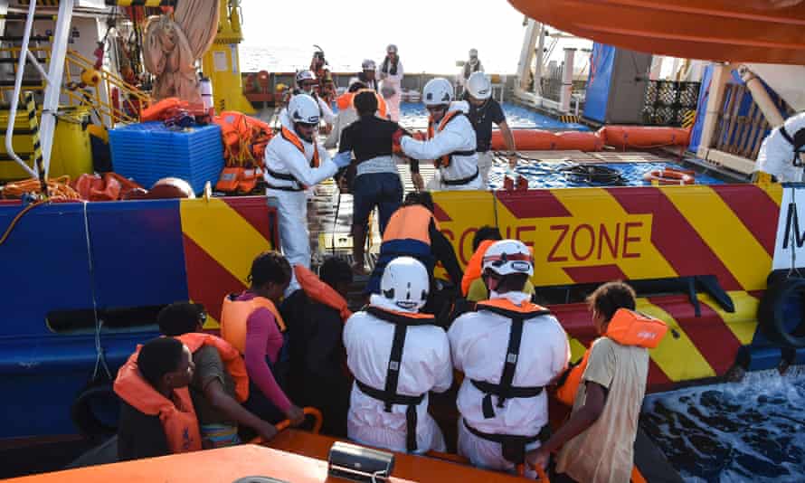 People are helped aboard the Topaz Responder ship during a rescue operation in the Mediterranean Sea